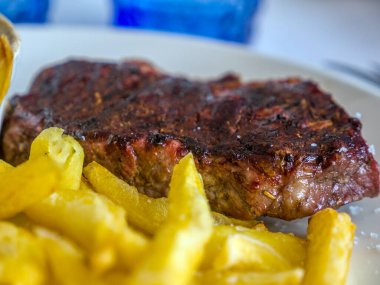 Tabakta patates kızartmasıyla servis edilen bifteğe bravo.