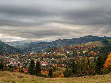 Bereketli tepeler ve bulutlu bir gökyüzü altında canlı sonbahar yapraklarıyla çevrili güzel bir köy olan Pieniny, Polonya