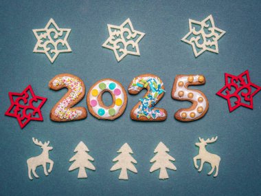 Brightly decorated numbers forming the year 2025 surrounded by assorted holiday-themed ornaments on a blue background, evoking cheerful festive and Christmas vibe clipart