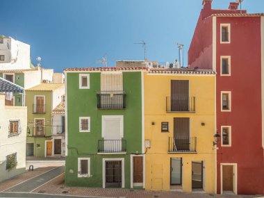 Colorful houses in a Mediterranean coastal town on a sunny day, against a vivid blue sky, Villajoyosa, Spain clipart