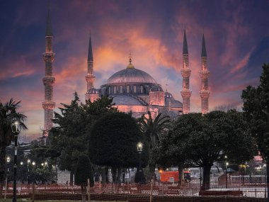 Gün batımında gökyüzüne karşı duran güzel ışıklandırılmış Mavi Cami karmaşık mimari ayrıntıları ve yükselen minareleri vurguluyor, İstanbul, Türkiye