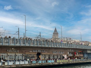İstanbul, Türkiye, Şubat, 16, 2025: Galata Köprüsü 'nün alt katındaki restoranları ve yukarıda balık tutan insanları görmek, İstanbul' un bu popüler gösterisine canlılık katıyor