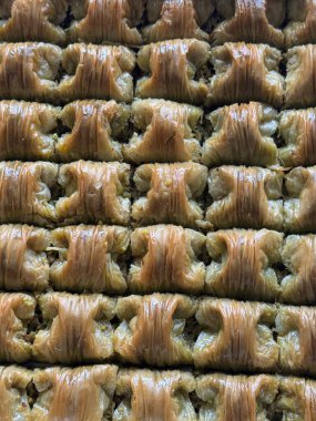 Şam fıstığı dolgulu altın sıra baklava şerbetle parıldayan hassas katmanlarını gösteriyor, işçiliğini ön plana çıkarıyor.