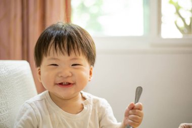 Asyalı erkek bebek yemek yedikten sonra mutfakta gülümser..
