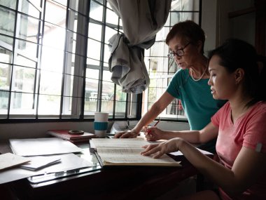 Asyalı kadın anne ve çocukları hesaplar hakkında tartıştılar ve evde bütçeyle tasarruf ve ödeme hakkında hesaplamalar yaptılar..