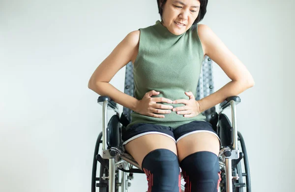 Patientin Leidet Unter Bauchschmerzen Und Sitzt Hause Rollstuhl lizenzfreie Stockbilder
