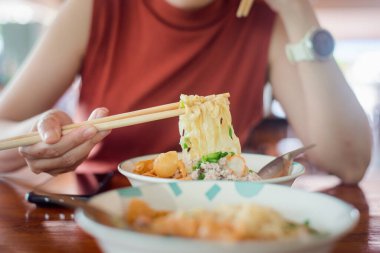 Kadın elleri lezzetli yumurtalı erişteyi yemek çubuğuyla tutuyor.