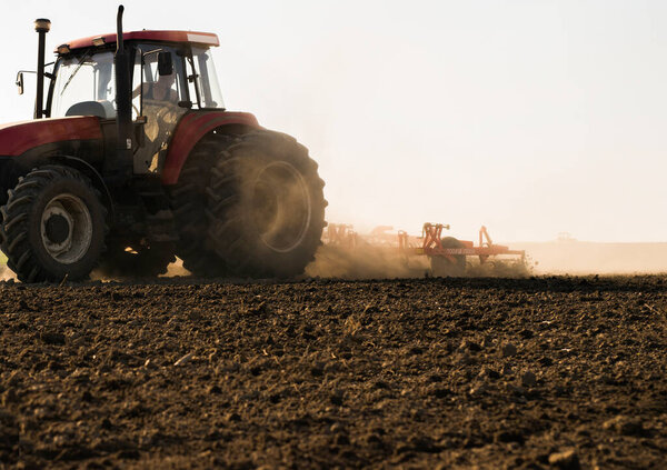 Фермер готовит поле на тракторе к весне.