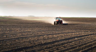 Traktörlü bir çiftçi güneş batarken tarlasını hazırlar.. 