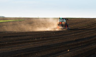 Traktörlü bir çiftçi güneş batarken tarlasını hazırlar.. 