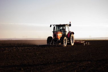 Traktörlü bir çiftçi güneş batarken tarlasını hazırlar.. 