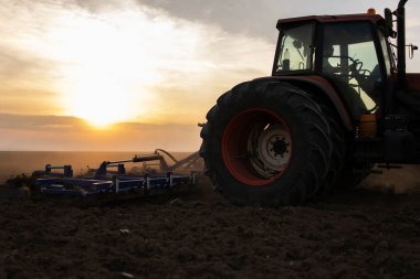 Traktörlü bir çiftçi güneş batarken tarlasını hazırlar.. 