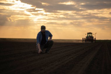  Satisfied tractor driver after work on agricultural field stands next to tractor. Farming and harvesting