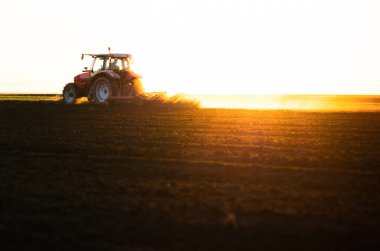 Traktörlü bir çiftçi güneş batarken tarlasını hazırlar.. 