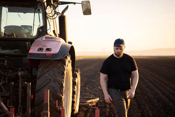 Mladý Zemědělec Kontrole Špína Zatímco Traktor Orat Pole — Stock fotografie