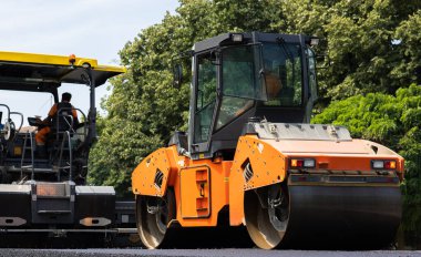 Makineler yol yapmak için döktükten sonra asfaltı eziyor 