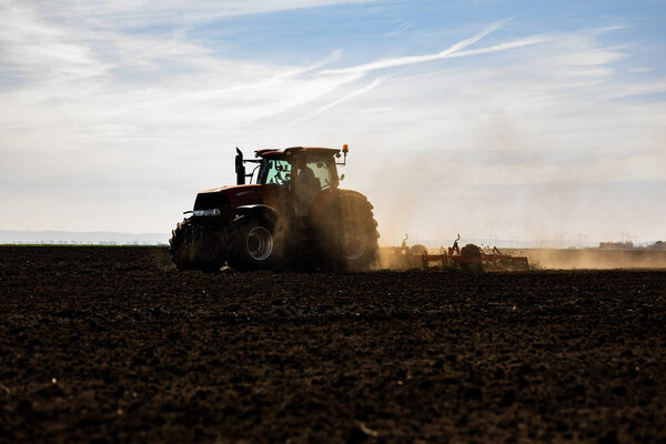 A farmer in a tractor prepares his field as the sun begins to set. 