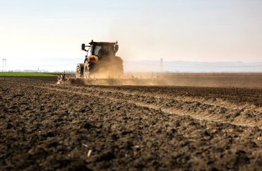 Traktörlü bir çiftçi güneş batarken tarlasını hazırlar.. 