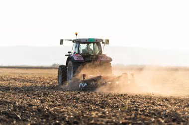 Traktörlü bir çiftçi güneş batarken tarlasını hazırlar.. 