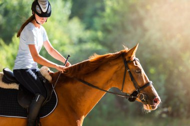 Genç bir kadın ata biniyor 