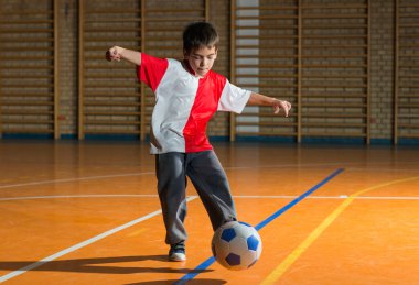 Küçük çocuk içeride gol atıyor.