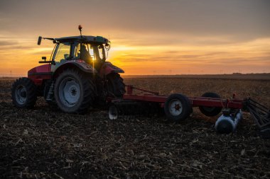 Traktörlü bir çiftçi güneş batarken tarlasını hazırlar.. 
