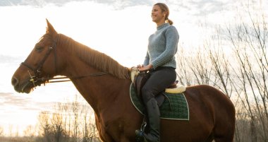 Genç bayan dışarıda atına bakıyor..