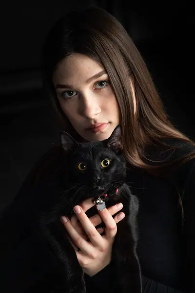 beautiful young woman in black sweater with black cat,