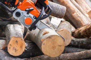 worker cuts firewood with a chainsaw