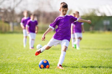 Küçük çocuk kaleye ateş ediyor, çocuk futbol topunu tekmeliyor. Genç futbolcu. Spor çocukları için eğitim.
