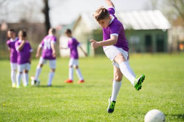 Küçük çocuk kaleye ateş ediyor, çocuk futbol topunu tekmeliyor. Genç futbolcu. Spor çocukları için eğitim.