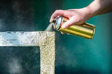 Çerçeveye altın boya serpiyor. Çerçeve resimleri için hazırlanıyor.