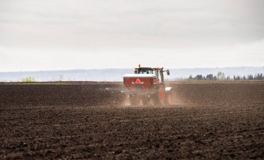 Traktör alana yapay gübre yayıyor.
