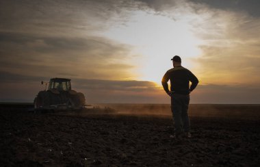 Traktör tarlayı iken genç çiftçiler incelenirken kir