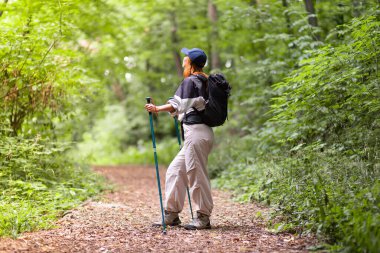 Orman yürüyüşü yapan kadın güz mevsiminde doğa arka planında yürüyor. Aktif insan yaşam tarzı yürüyüşü sırt çantası takmak dışarıda egzersiz yapmak..