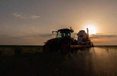 Bir traktör haşereleri ve yabani otları kontrol etmek için kimyasallar püskürtür.