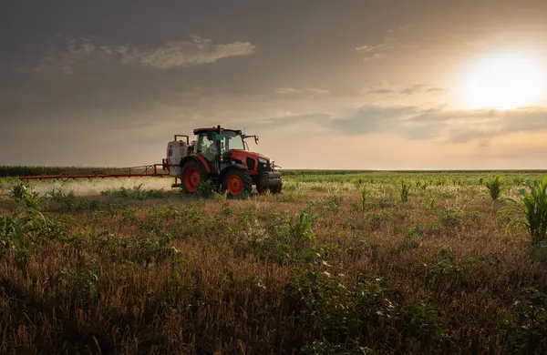 stock image A tractor sprays chemicals to control pests and weeds in crops