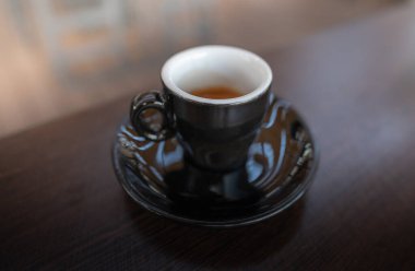 Bir fincan bitmemiş kahve restorandaki ahşap bir masada duruyor.