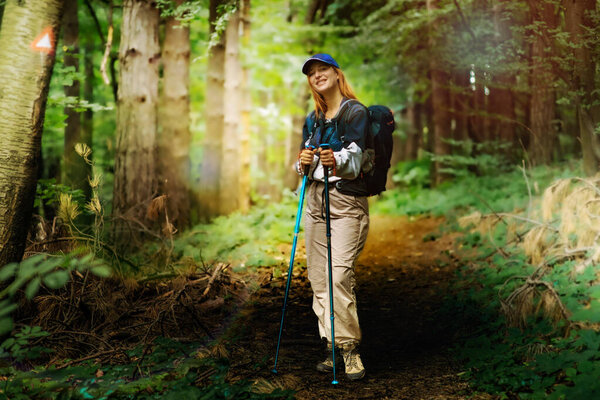 Hiking in the forest. Beautiful young women with big backpack hiking in the deep forest