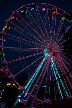 Gece boyunca Luna parkında renkli bir dönme dolap. Dönme dolabın uzun pozlu dikey fotoğrafı. 