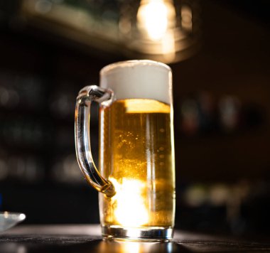 Bir bira bardağı kızağın üstünde duruyor. Köpüklü ve köpüklü altın bira