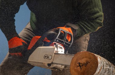 worker cuts firewood with a chainsaw