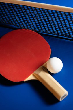 İki masa tenisi raketi ve topları mavi bir masada ağlı..