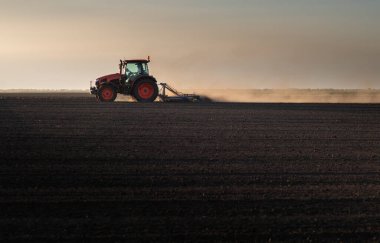 Traktör sürme çiftliği akşam yeni ekin ekimi için toprağı hazırlıyor..