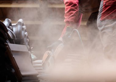  Bir işçi, çatı için kırmızı seramik kiremitler kesiyor.