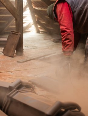  Bir işçi, çatı için kırmızı seramik kiremitler kesiyor.