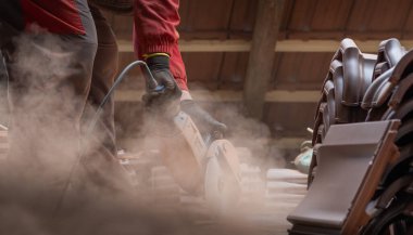  Bir işçi, çatı için kırmızı seramik kiremitler kesiyor.