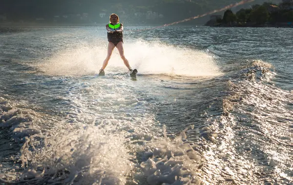 Gün batımında denizde su kayağı yapan genç bir kadın..