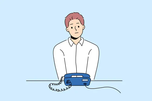 不快乐的男人坐在办公桌前看着固定电话等人打电话 沮丧的家伙在等待戒指看着绳状电话 矢量说明 — 图库矢量图片