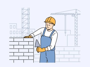 Üniformalı ve miğferli tuğlalı ev yapan pozitif erkek işçi. Gülümseyen mühendis inşaat alanında blok yapmakla meşgul. Vektör illüstrasyonu. 